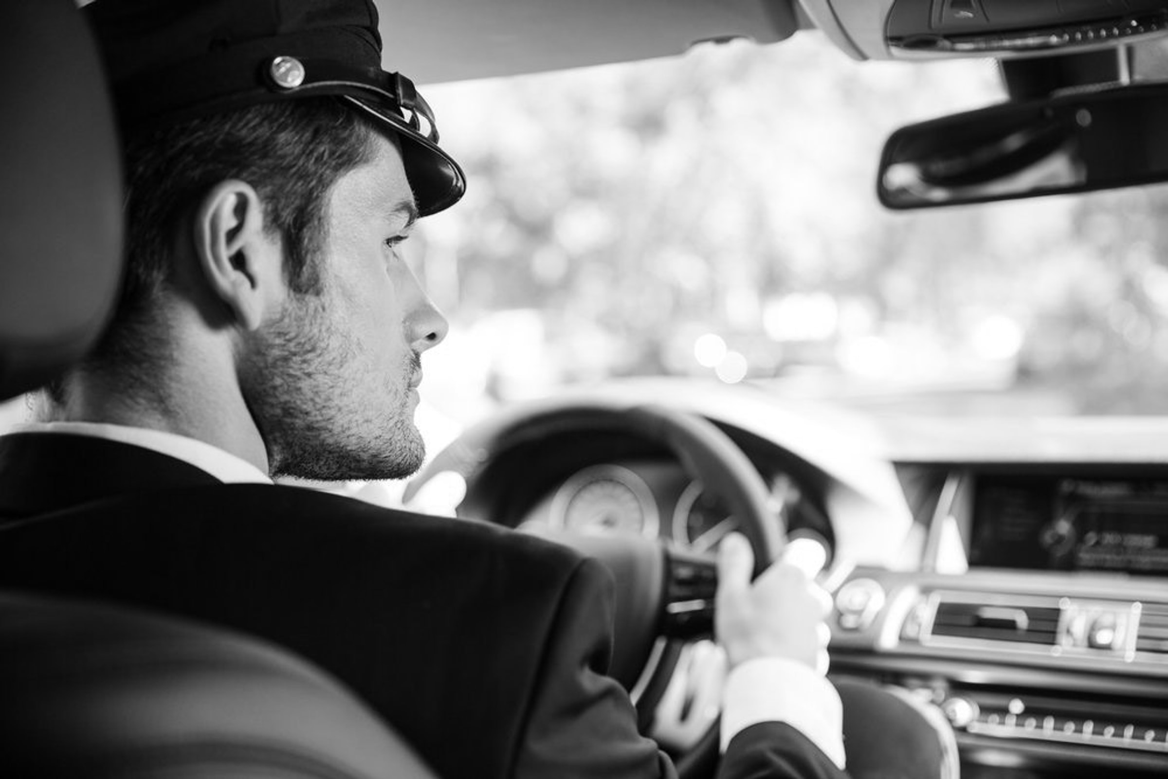 Chauffeur in formal attire beside a luxury vehicle